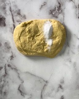 Un pezzo di pasta è appoggiato su una superficie di marmo.