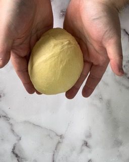Una persona tiene in mano una palla di pasta.
