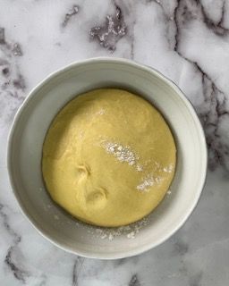 Una ciotola di salsa gialla è appoggiata su una superficie di marmo.