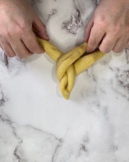 Una persona sta attorcigliando un pezzo di pasta su una superficie di marmo.