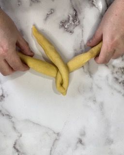 Una persona sta attorcigliando un pezzo di pasta su una superficie di marmo.