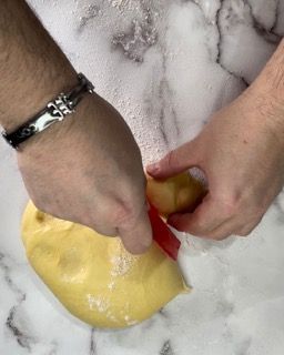 Una persona che indossa un braccialetto tiene in mano un pezzo di pasta