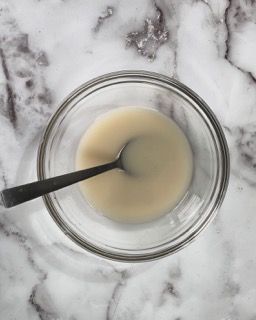 Una ciotola di salsa con un cucchiaio dentro su un tavolo.