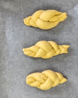 Tre panini intrecciati sono appoggiati su un pezzo di carta oleata