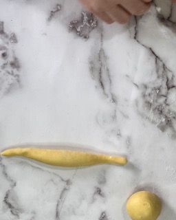Una persona sta stendendo la pasta su un tavolo di marmo.