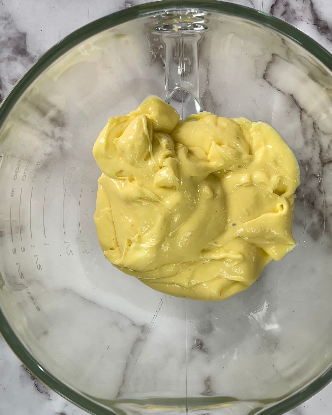 Una ciotola di vetro piena di un liquido giallo su un tavolo.