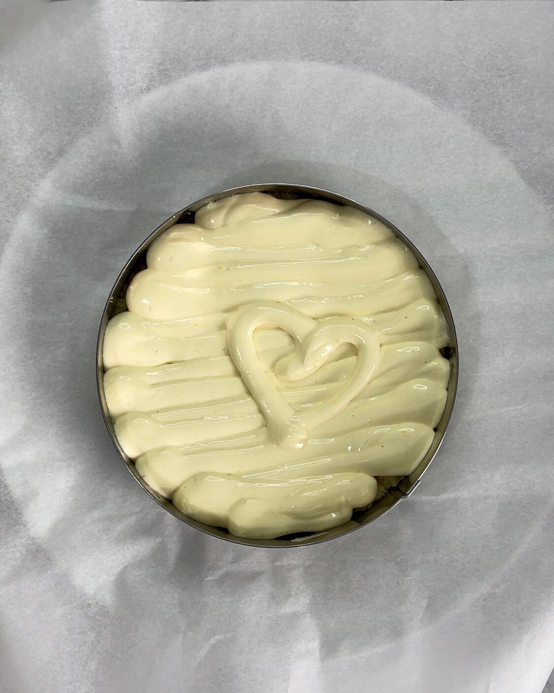 Una torta con un cuore sopra è appoggiata su un pezzo di carta oleata.