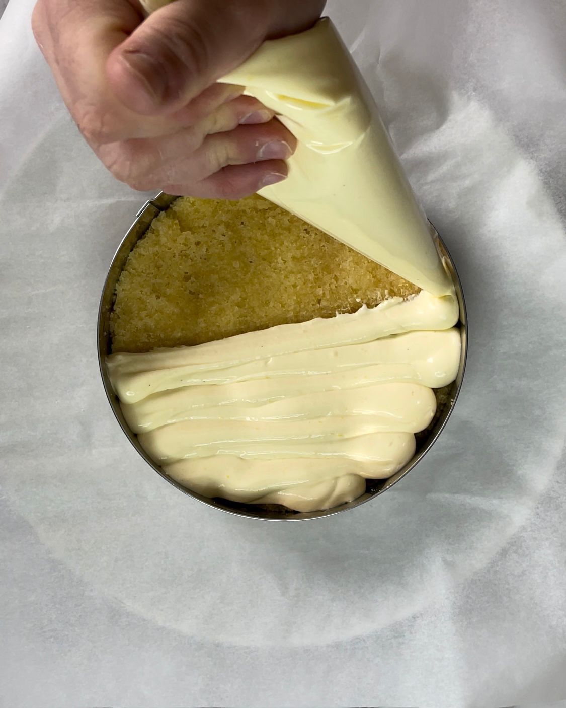 Una persona sta usando una sac à poche per riempire una torta con la glassa.