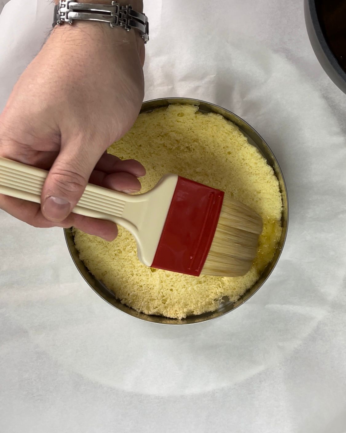 Una persona tiene in mano un pennello sopra una torta.