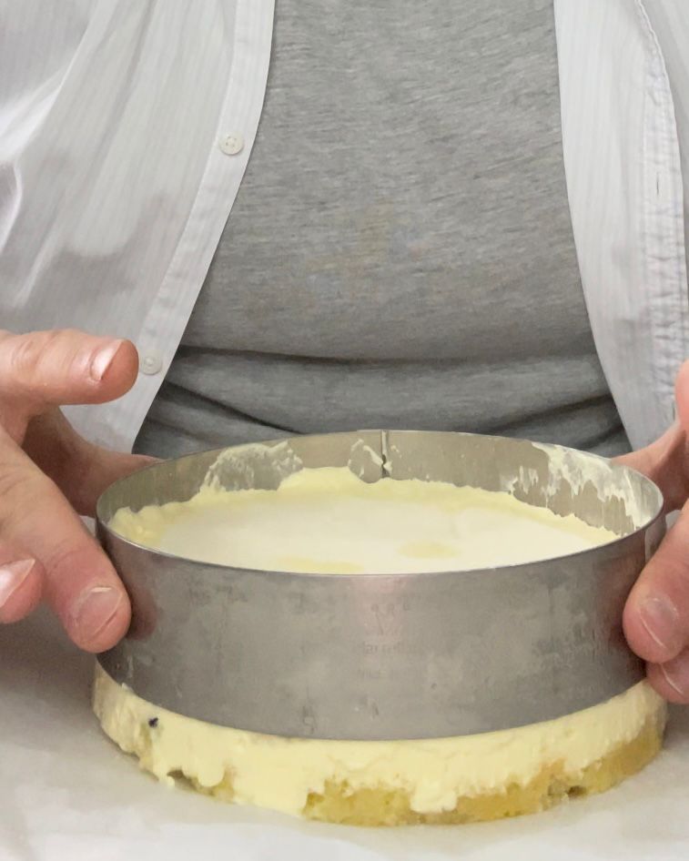 Una persona tiene una torta in un anello di metallo.