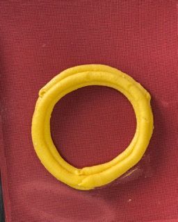 Un anello giallo è appoggiato su un panno rosso.