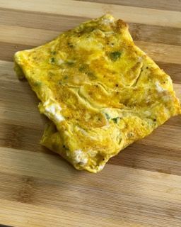 Primo piano di una frittata su un tagliere di legno.