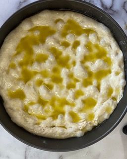 Un impasto per pizza in una padella con olio d'oliva sopra.