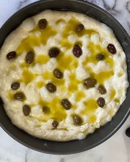 Una pizza con olive e olio d'oliva in padella.
