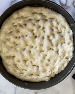 Un impasto per pizza è in una teglia su un tavolo.
