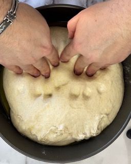 Una persona sta impastando l'impasto con le mani in una padella.