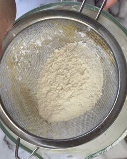 Una persona sta setacciando la farina in una ciotola.