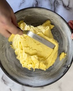 Una persona tiene una spatola sopra una ciotola di purè di patate