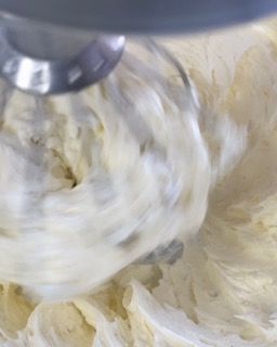 Primo piano di un mixer che mescola il formaggio cremoso in una ciotola.