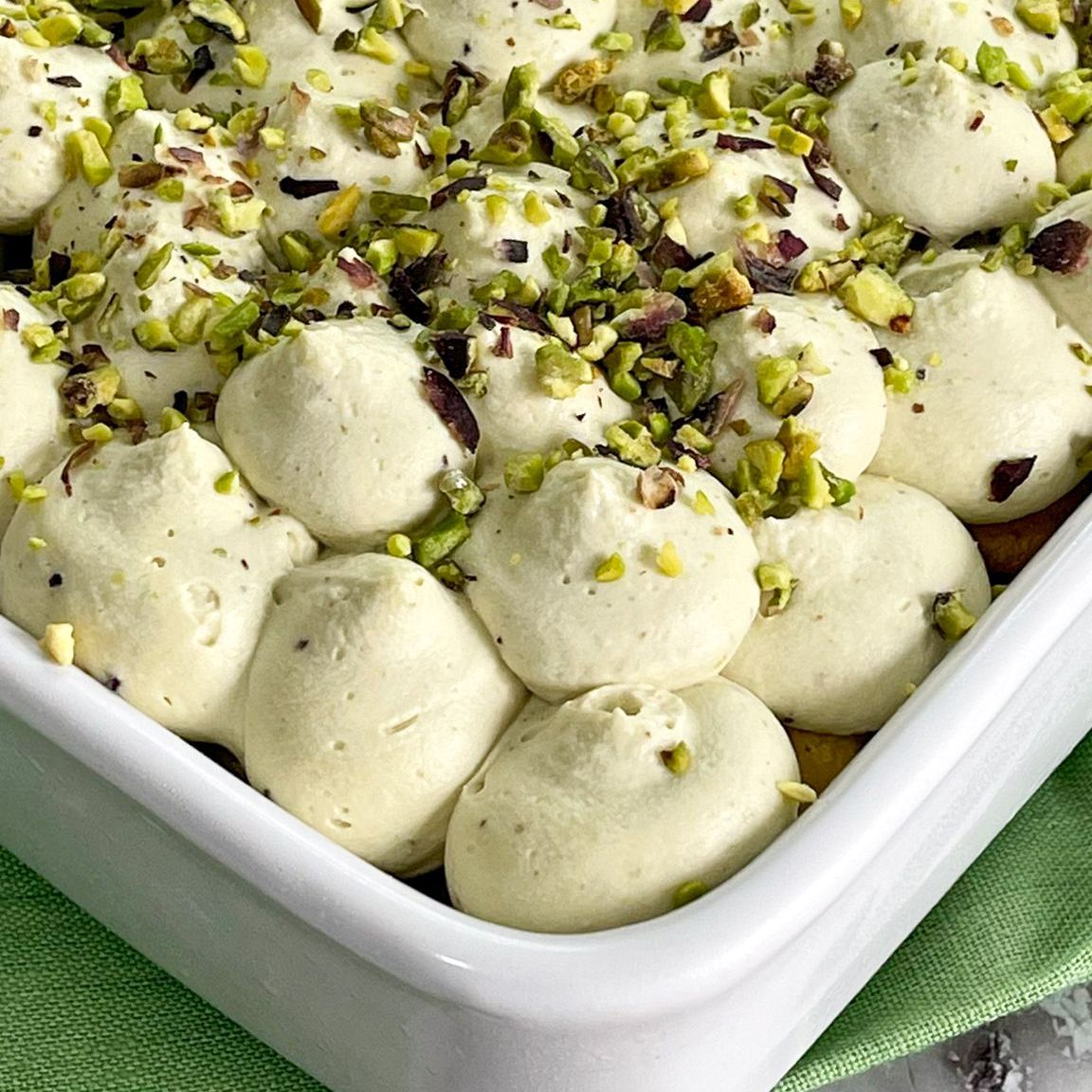 Una teglia bianca ripiena di panna montata e pistacchi