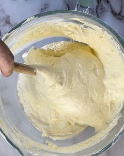 Una persona sta mescolando un liquido giallo in una ciotola di vetro con un cucchiaio di legno.