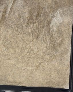 Un pezzo di carta marrone è appoggiato su un vassoio nero.