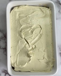 Una pirofila bianca piena di glassa verde su un tavolo.