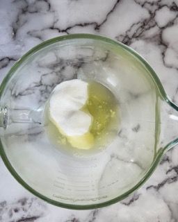 Su un tavolo c'è un misurino di vetro con un cucchiaio dentro.