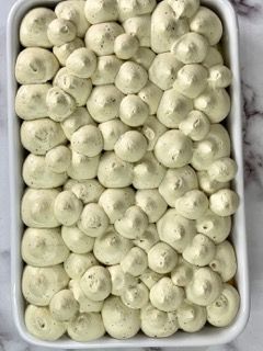 Una pirofila bianca piena di panna montata e marshmallow.