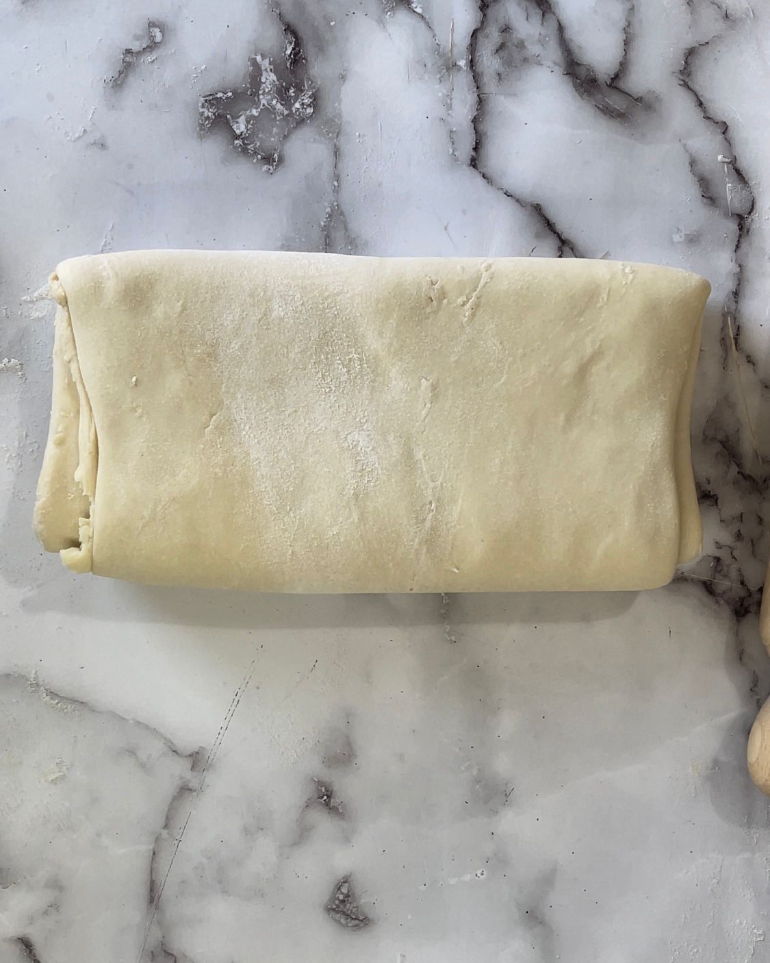 Un pezzo di pasta è appoggiato su un bancone di marmo.