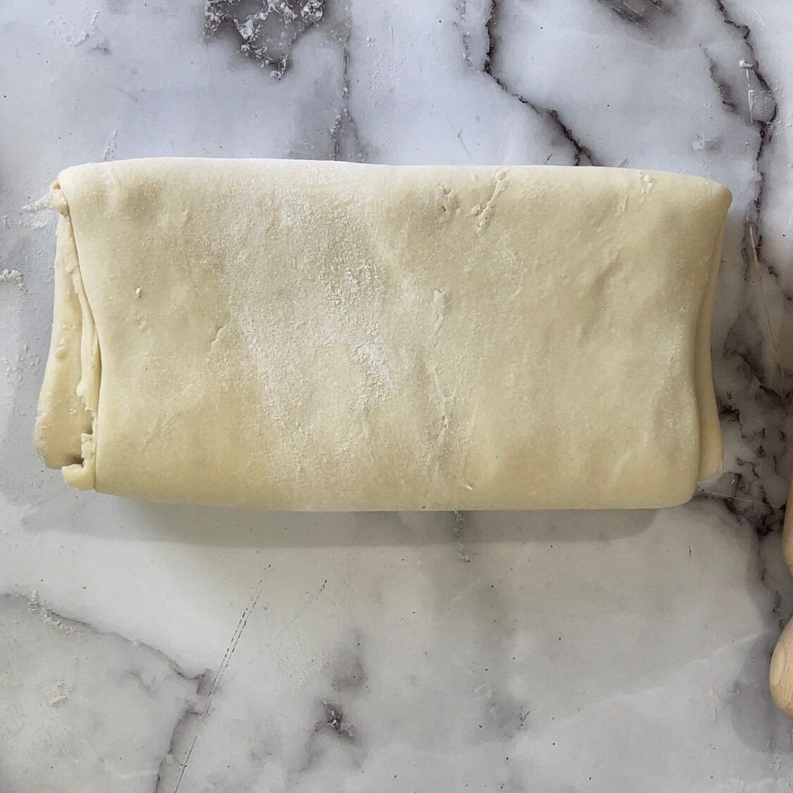 Un pezzo di pasta è appoggiato su una superficie di marmo.