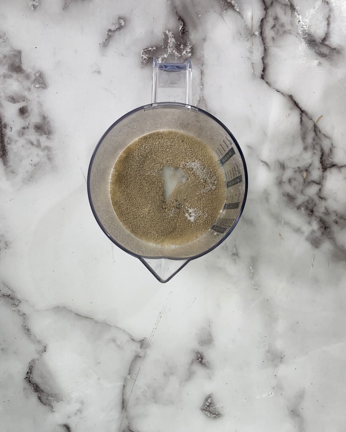 Un frullatore è riempito con un liquido marrone su una superficie di marmo.
