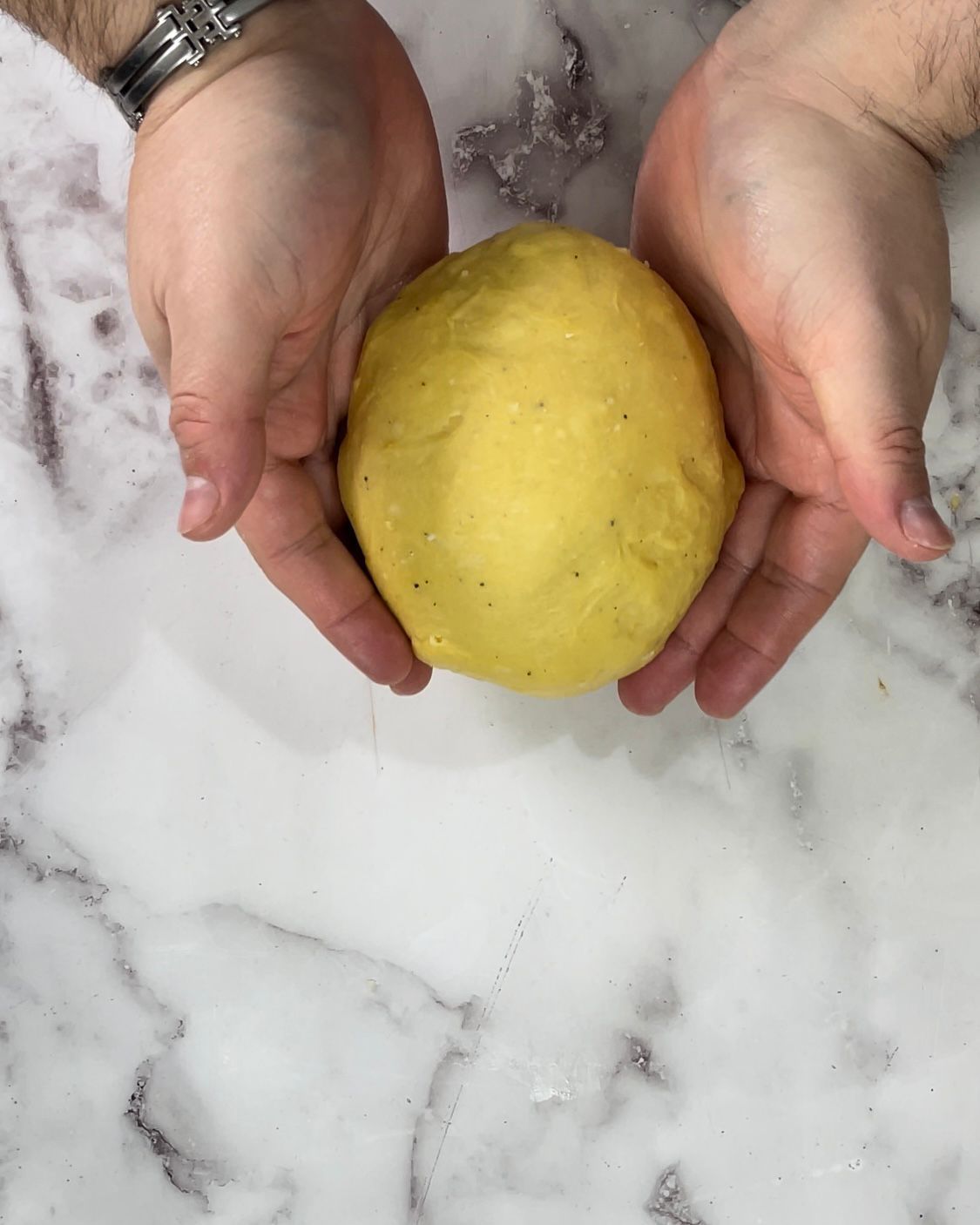 Una persona tiene in mano una palla di pasta gialla.