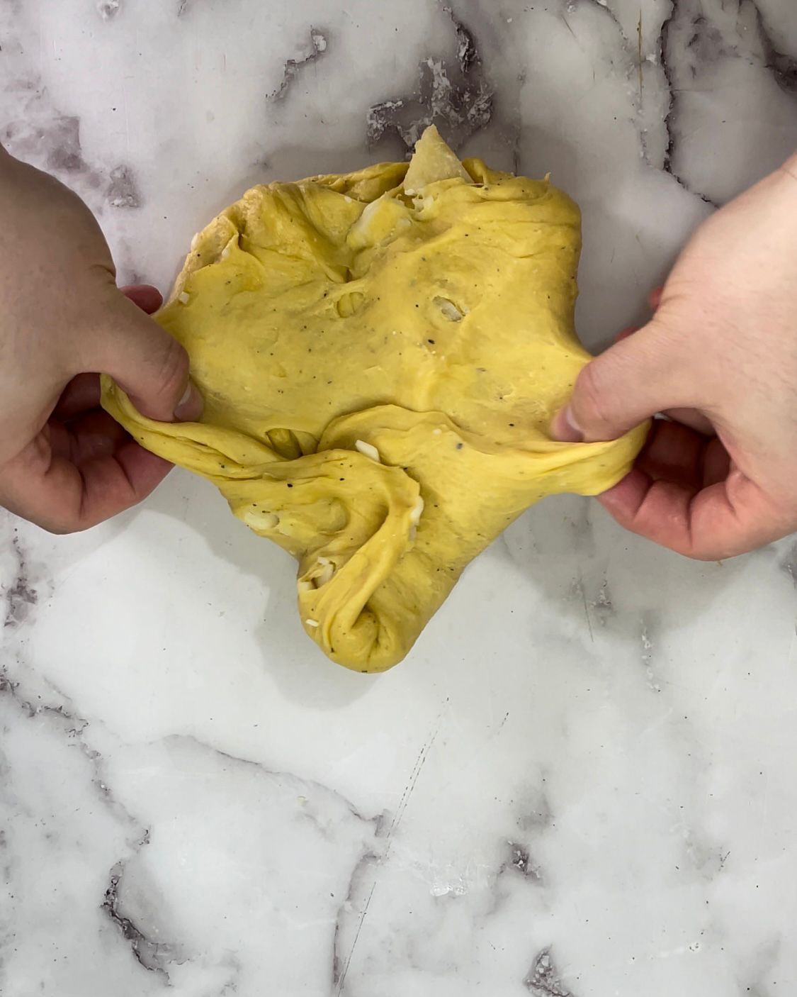 Una persona tiene in mano un pezzo di pasta gialla.