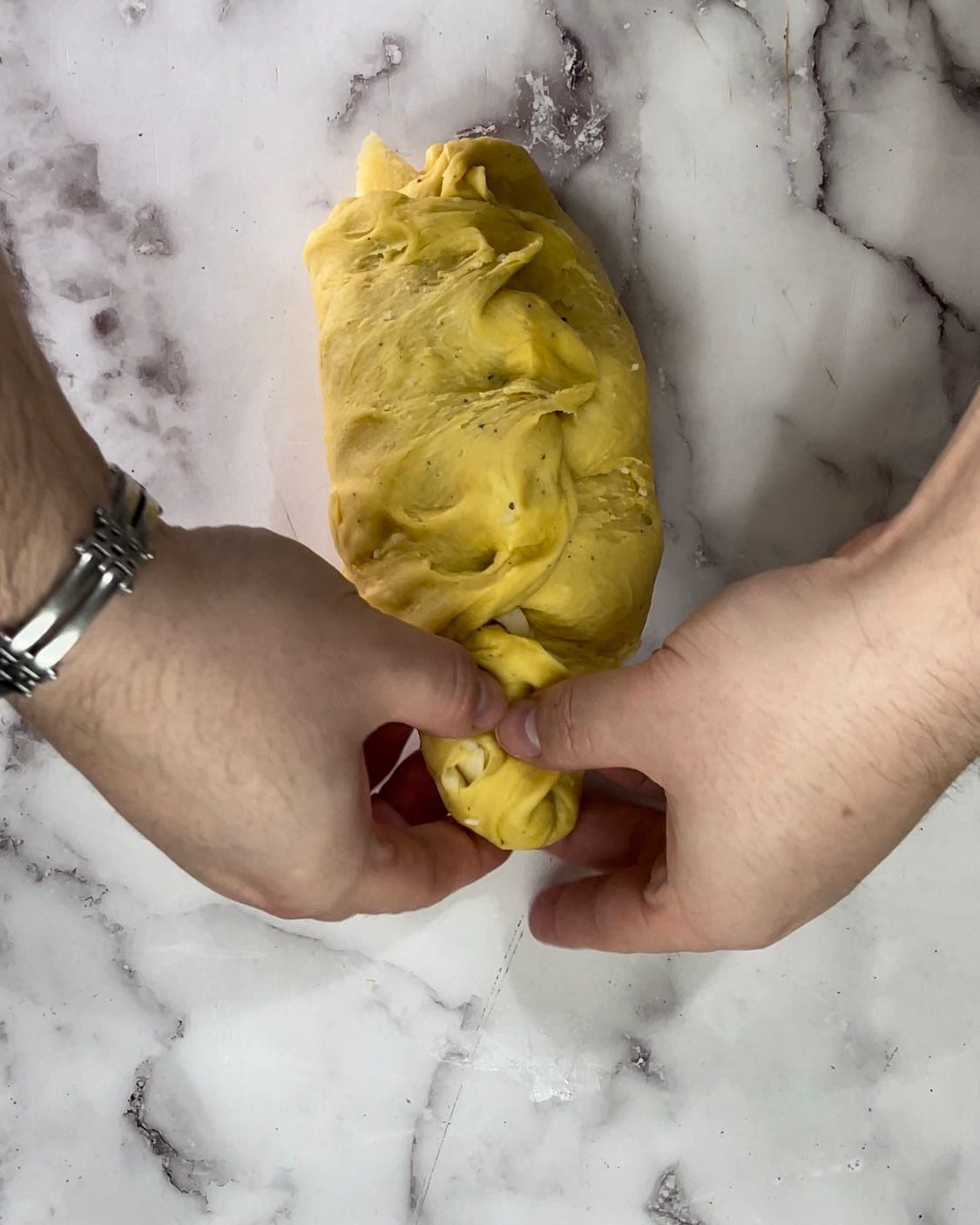 Una persona tiene in mano un pezzo di pasta gialla.
