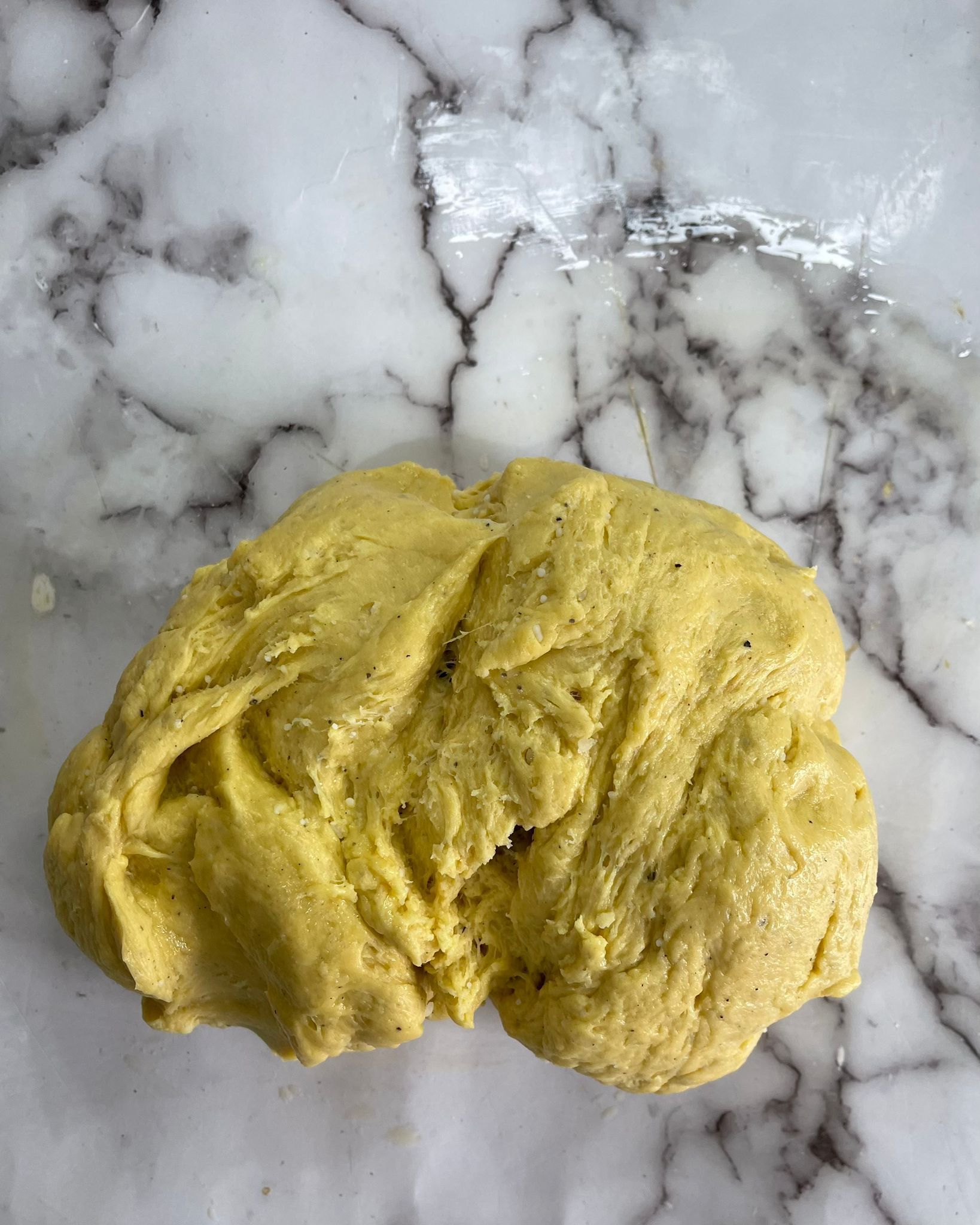Primo piano di una palla di pasta su una superficie di marmo.