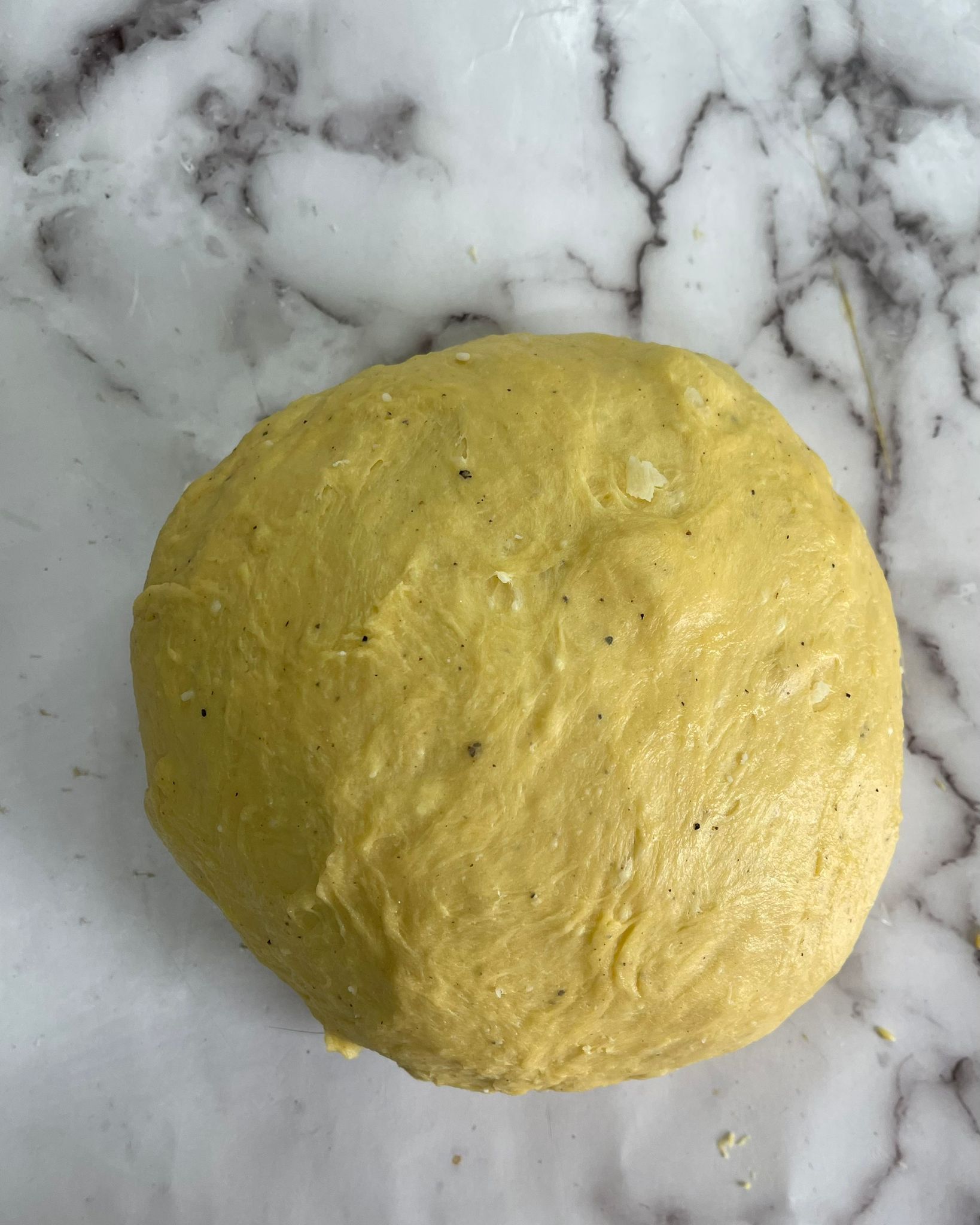Una palla di pasta è appoggiata su una superficie di marmo.