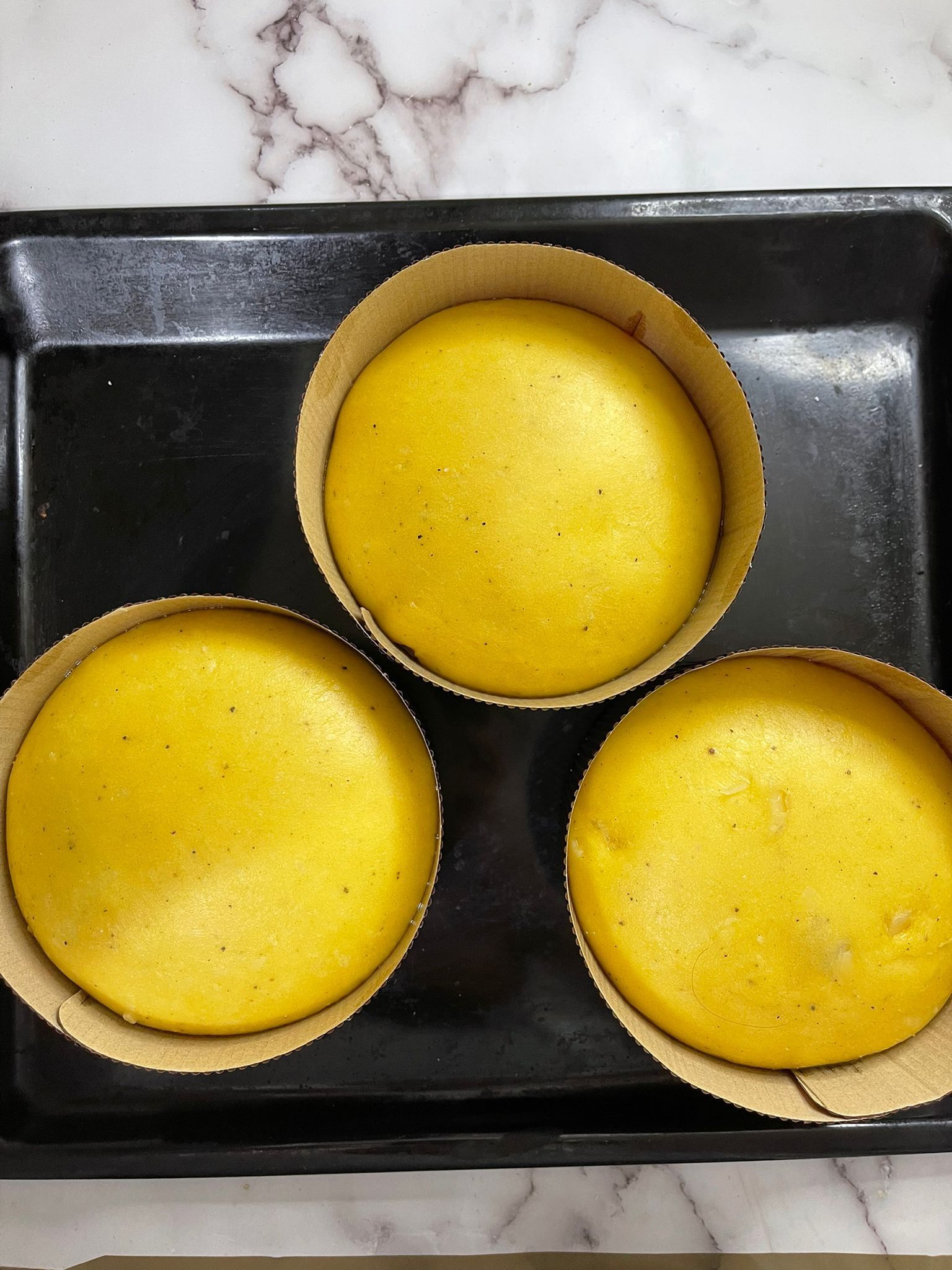 Tre torte gialle sono appoggiate su un vassoio nero