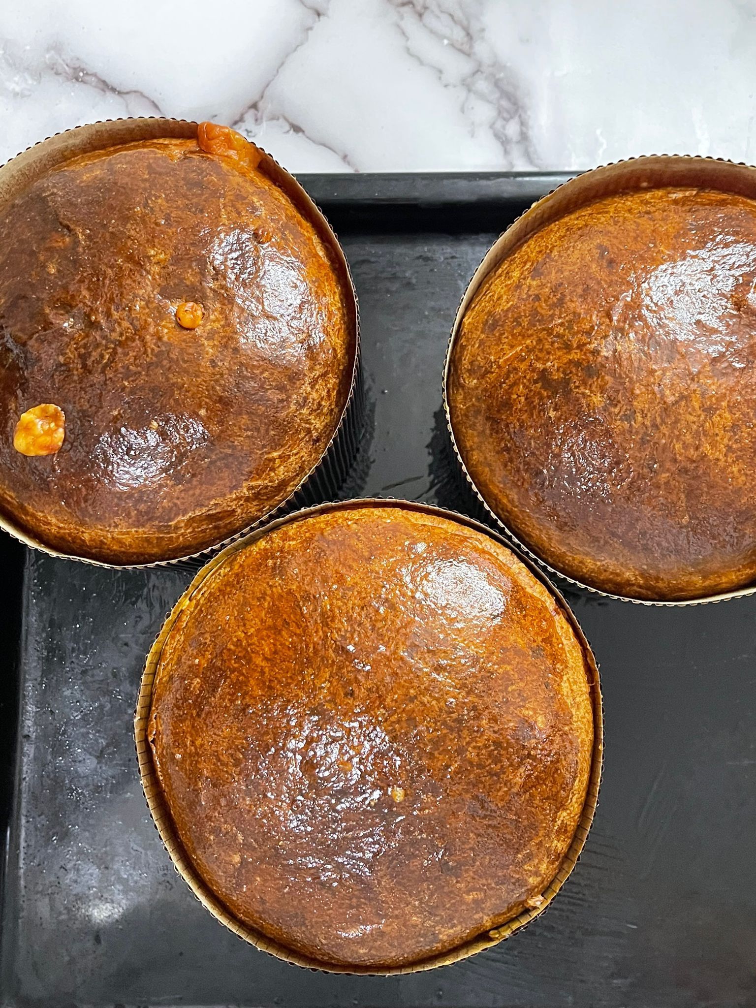 Tre torte sono appoggiate su un vassoio nero su un tavolo.