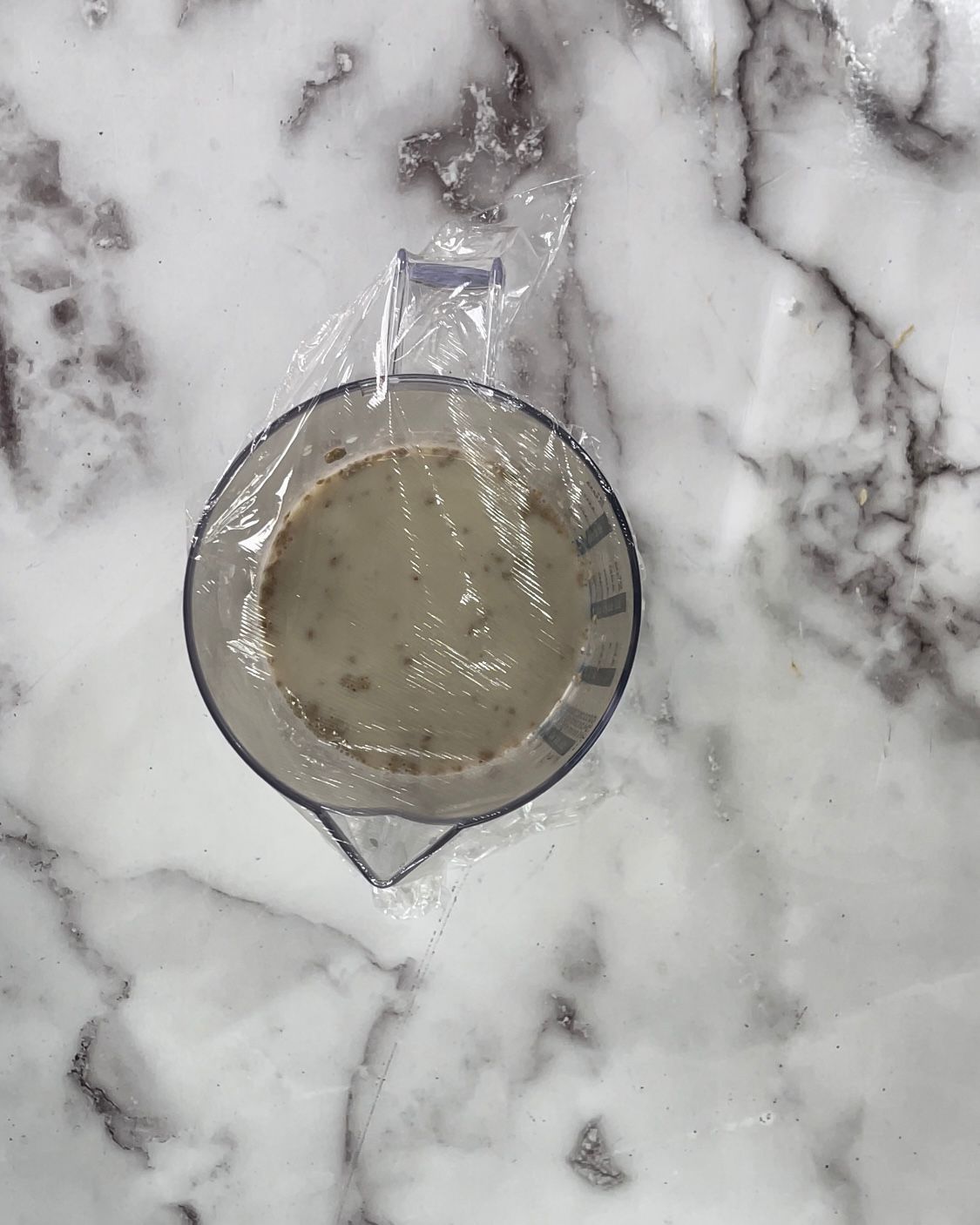 Un misurino pieno di liquido è appoggiato su una superficie di marmo.