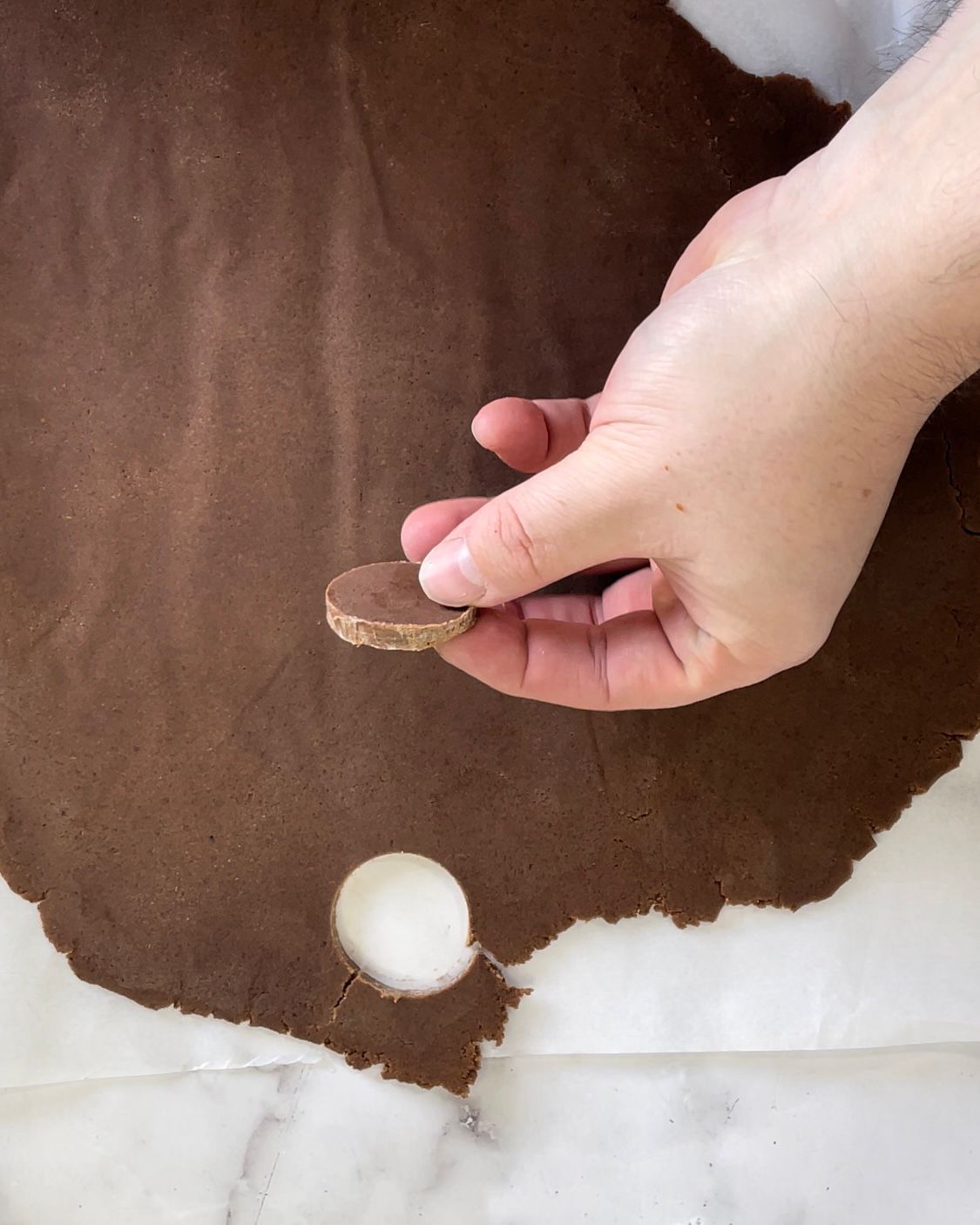 Una persona sta tagliando un biscotto da un pezzo di pasta al cioccolato.