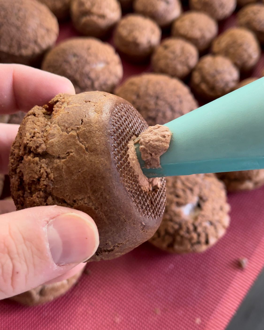 Una persona sta glassando un muffin al cioccolato con una sac à poche