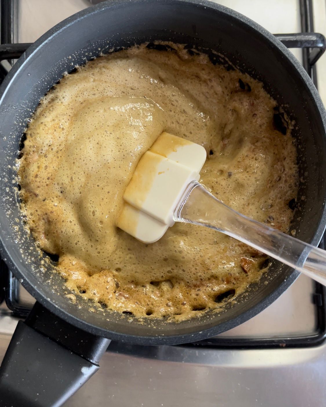 Una spatola viene utilizzata per mescolare una salsa in una padella
