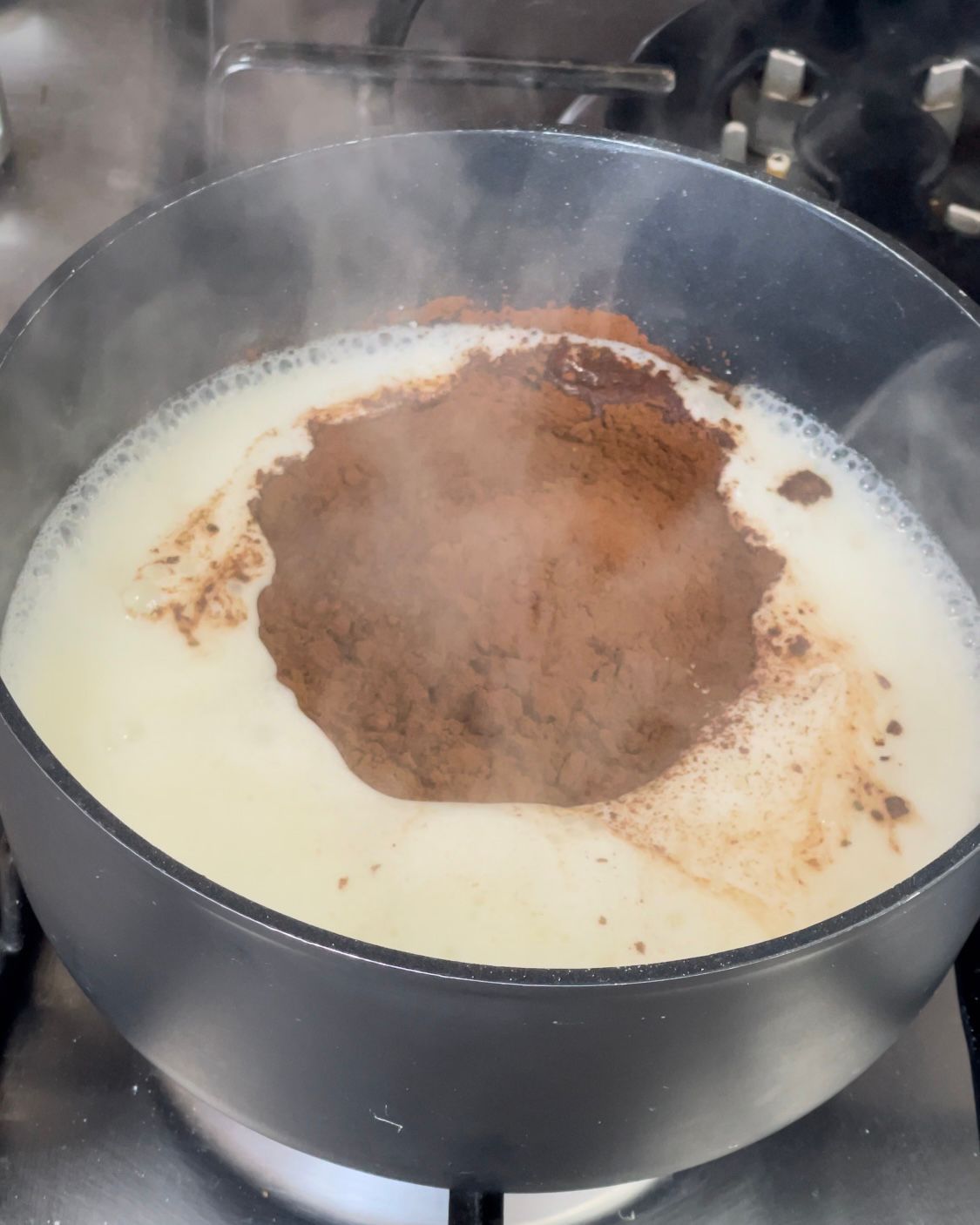 Una pentola di latte e cacao in polvere su un fornello