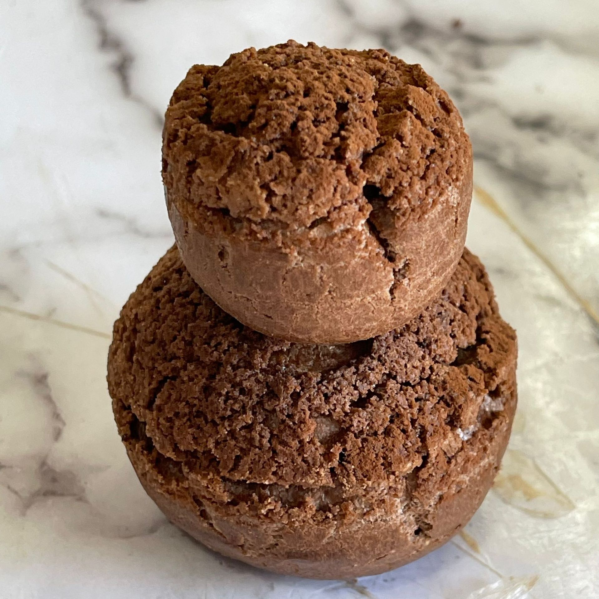 Due biscotti al cioccolato sono impilati uno sopra l'altro su una superficie di marmo