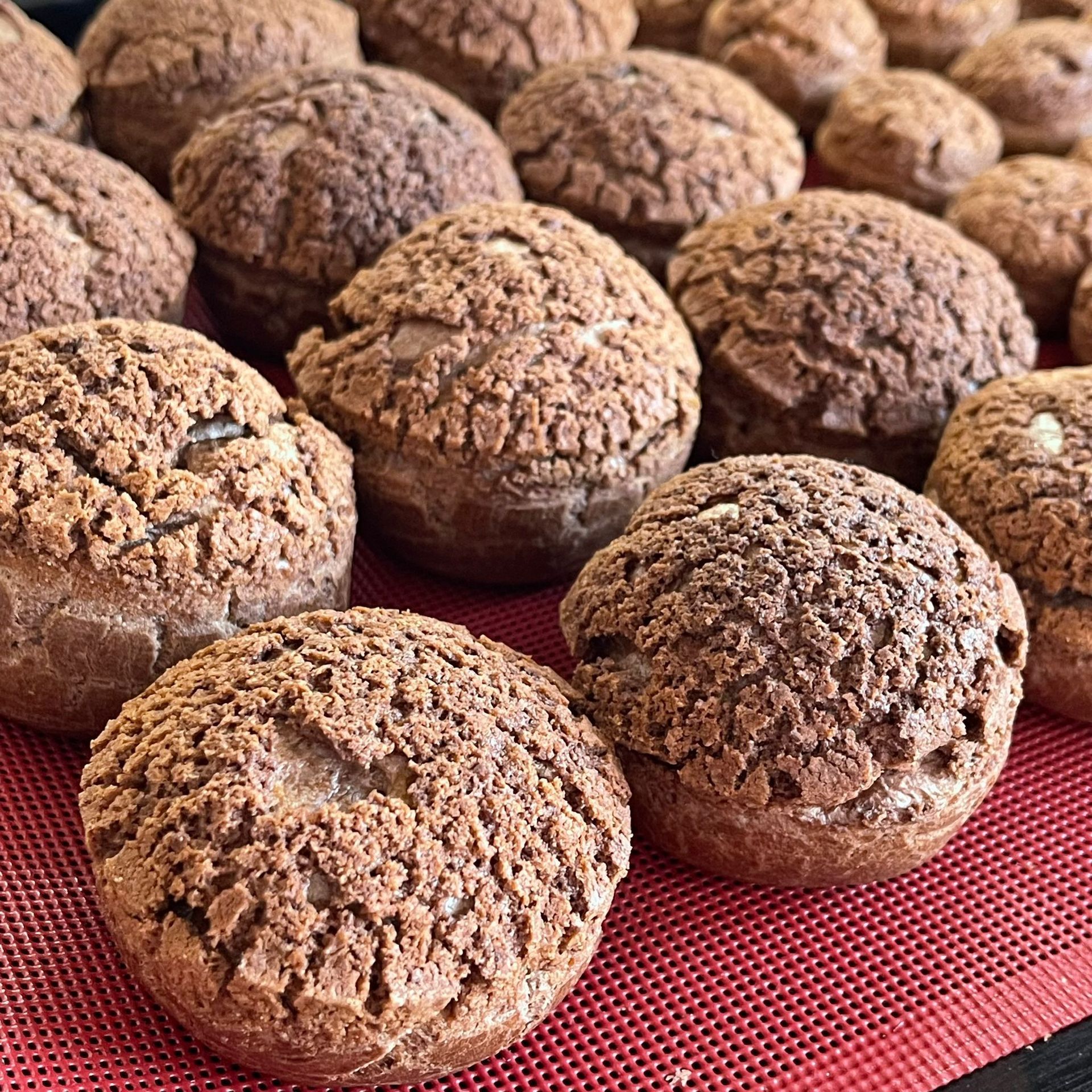 Un mucchio di tortine al cioccolato sono appoggiate su un tappetino rosso.