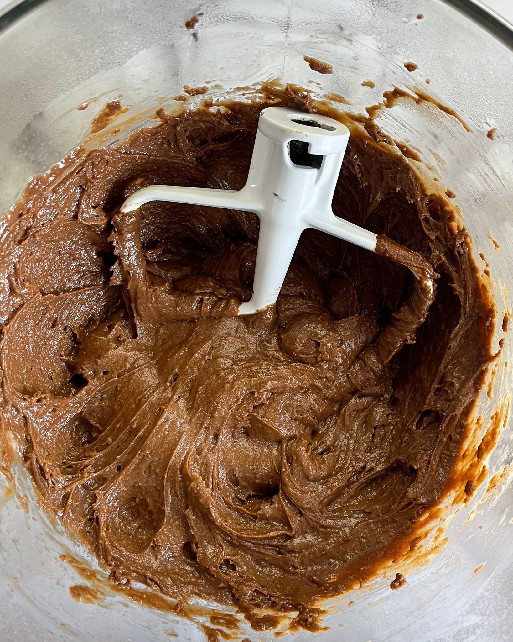 Primo piano di una ciotola di impasto al cioccolato con dentro uno sbattitore.