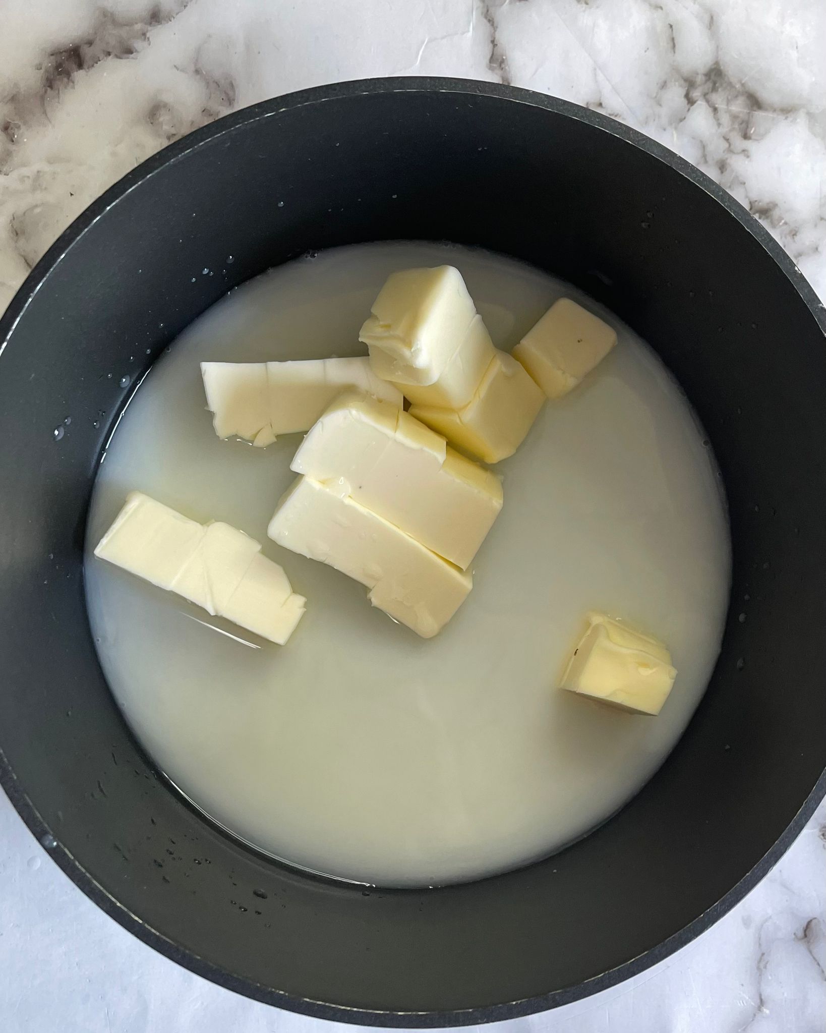 Una pentola piena di latte e burro su un tavolo.