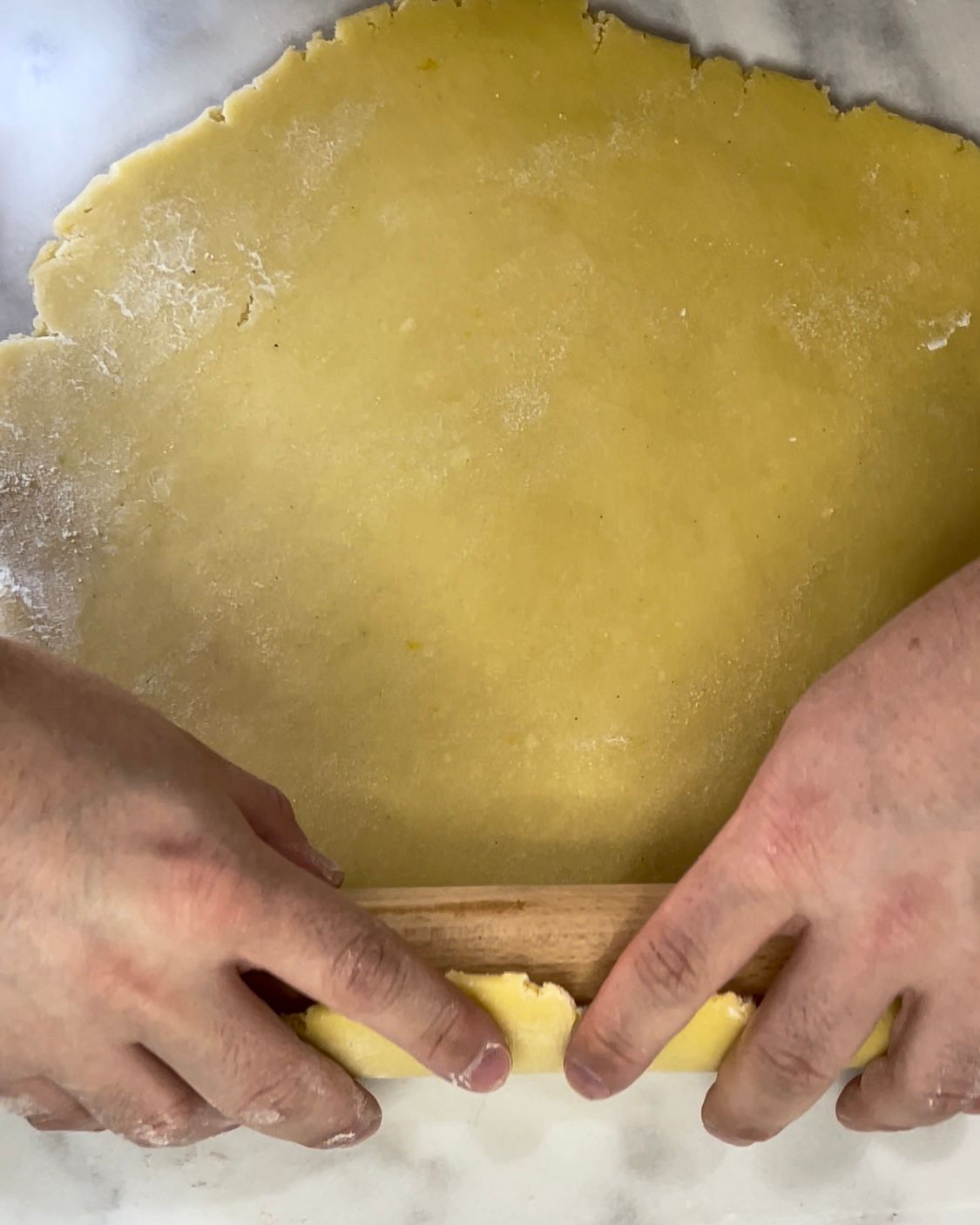 Una persona sta stendendo la pasta con il mattarello.