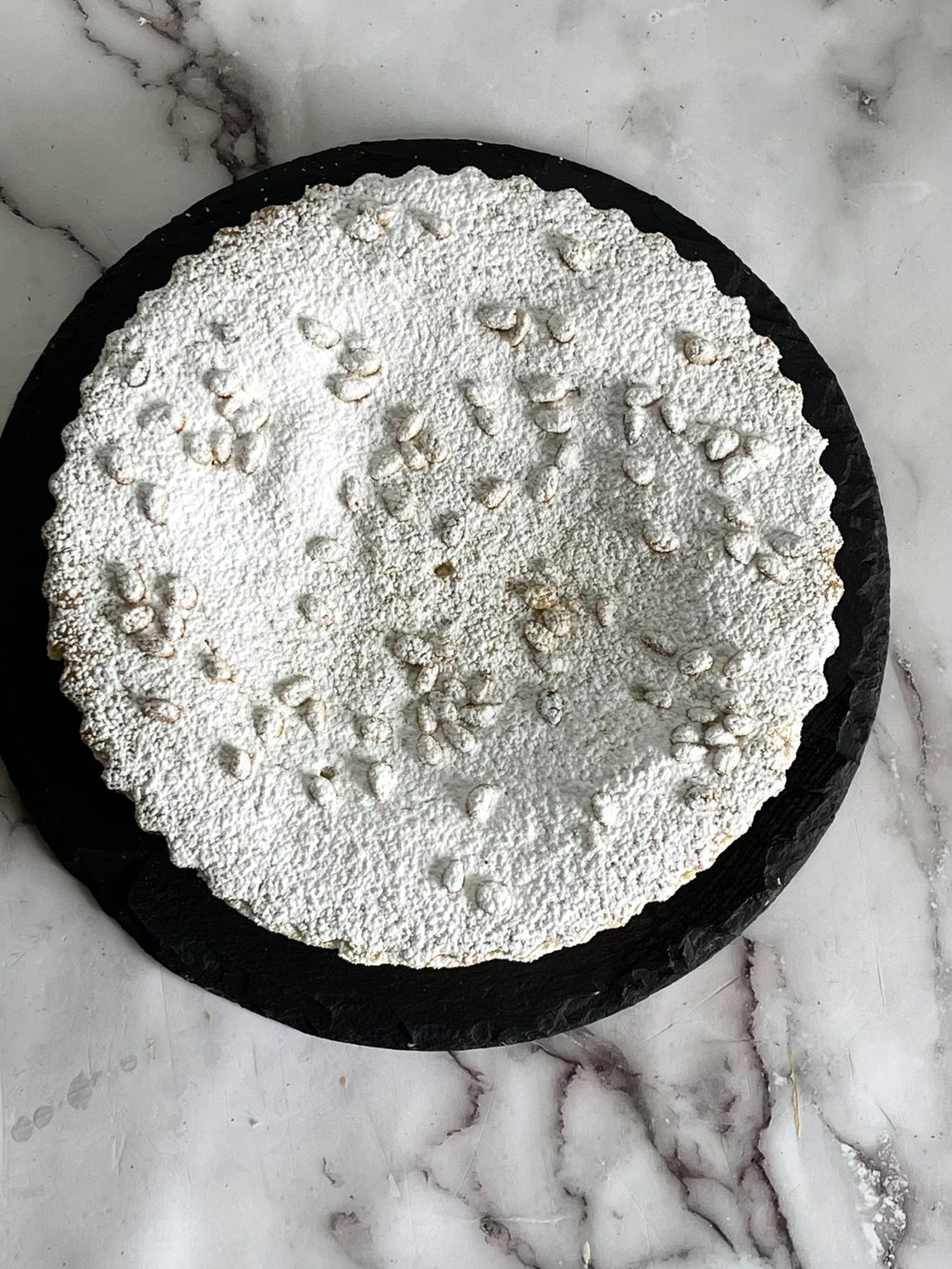 Un piatto bianco con il bordo nero è appoggiato su una superficie di marmo.